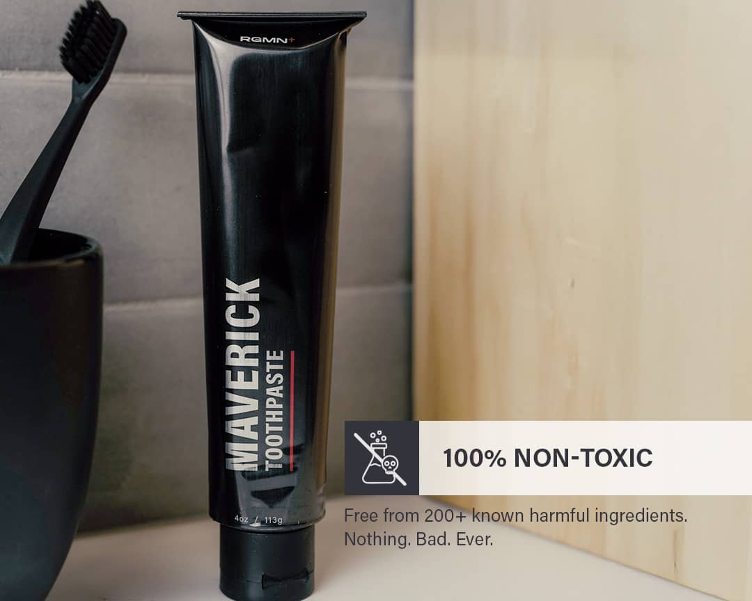 RGMN+ toothpaste tube with a black toothbrush and cup on a bathroom counter, featuring fluoride-free and non-toxic information.