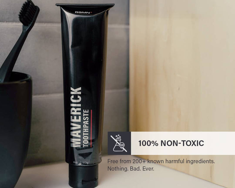 RGMN+ toothpaste tube with a black toothbrush and cup on a bathroom counter, featuring fluoride-free and non-toxic information.